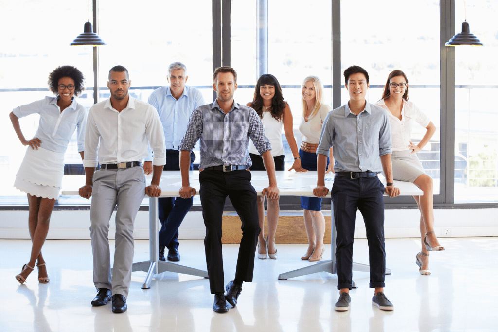 A group of business administrators stand around a conference table in an office