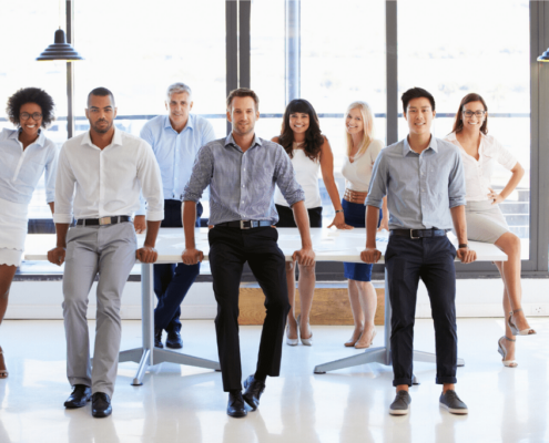 A group of business administrators stand around a conference table in an office
