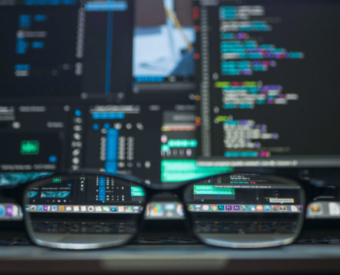 A pair of glasses sit in front of a computer screen featuring cybersecurity data