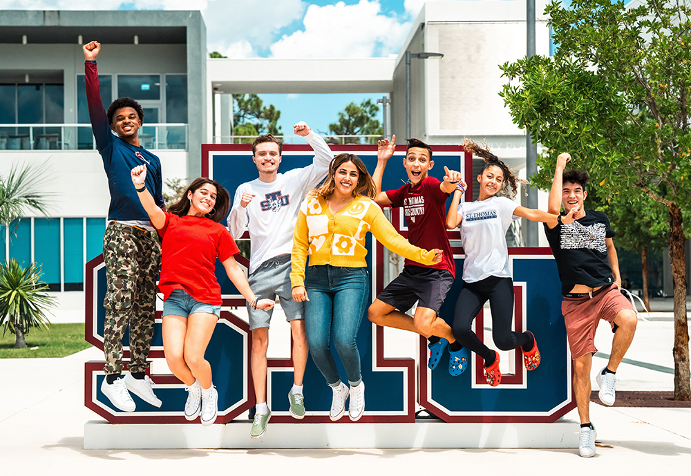 Students jumping in front of STU sculpture
