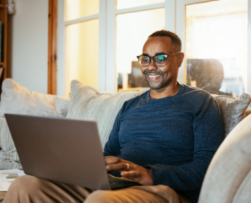 Adult student using a laptop at home to complete online coursework for a finance degree program.