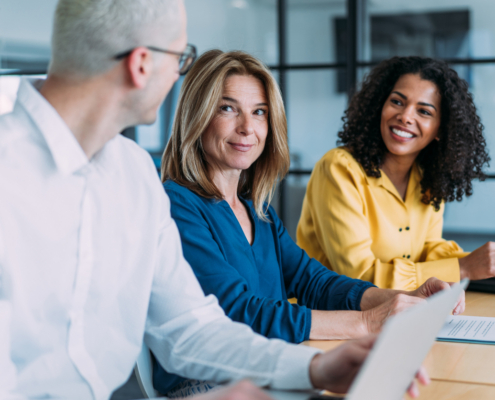 Professionals collaborating in a business meeting, reviewing documents and discussing work in a modern office.