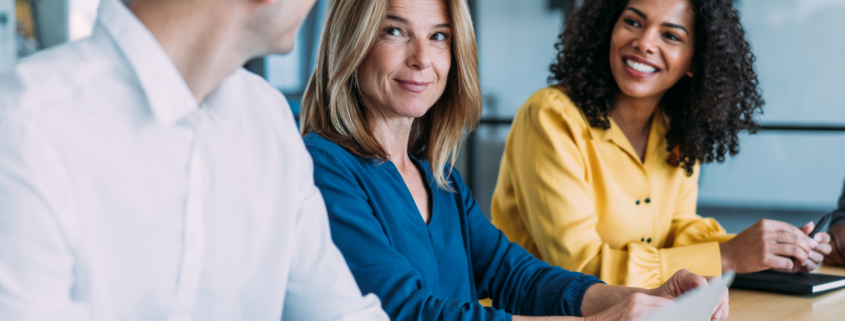Professionals collaborating in a business meeting, reviewing documents and discussing work in a modern office.